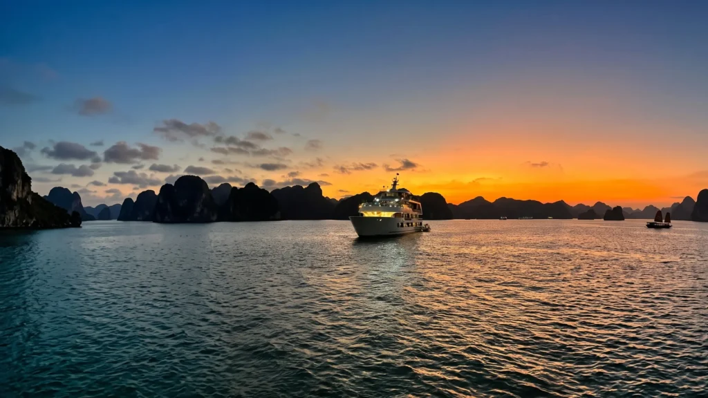 Halong Bay cruise ship at sunset among limestone karsts