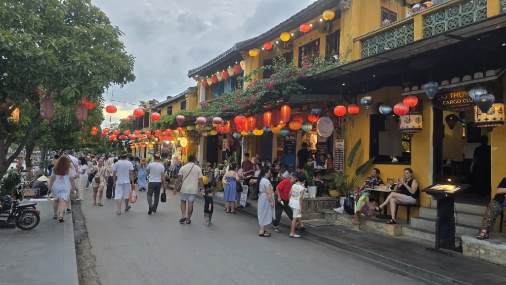 lantern-lined street in Hoi An Old Town at dusk with cafes and shoppers