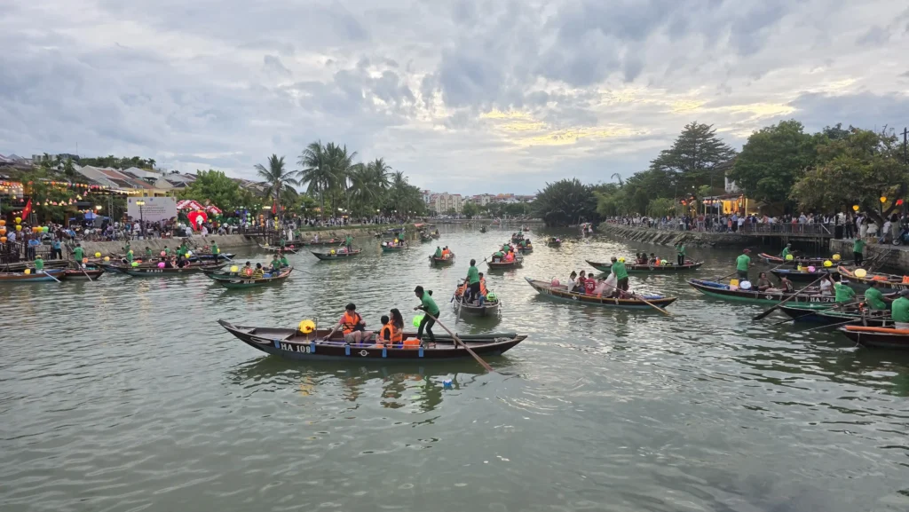 rowing boats full of visitors on the Hoai River in Hoi An before sunset