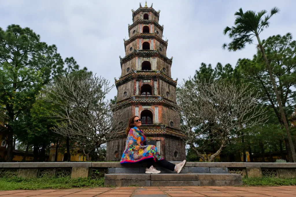 Traveler sitting in front of Thien Mu Pagoda's seven-tiered tower in Hue