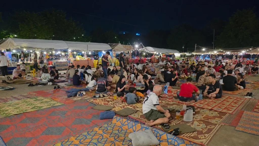 Local night market stall in Phnom Penh with people eating on mats