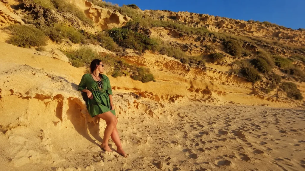 Traveler pausing on a sandy dune along Ibiza's coastline at golden hour.