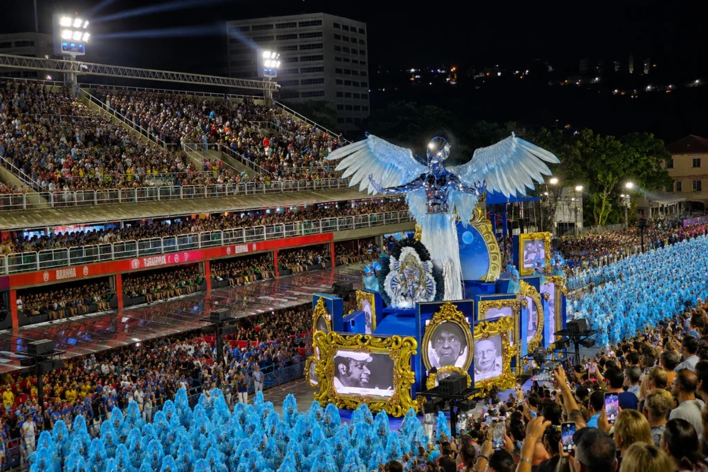 Samba school performers in blue feathered costumes parading through the Sambadrome during Rio Carnival