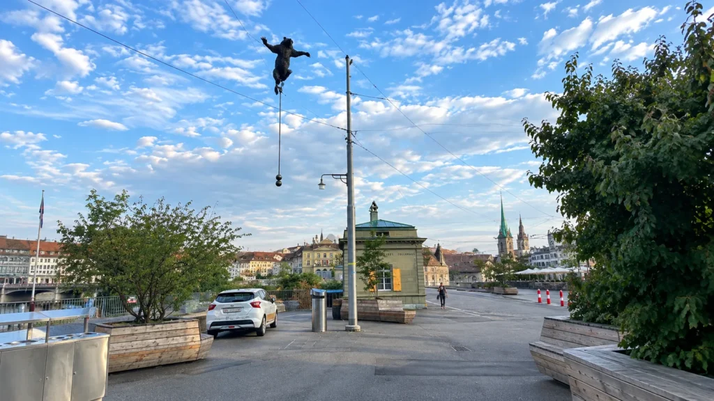 A bear sculpture balanced on a wire above a square near Bern's Nydeggbrücke