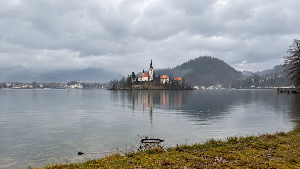 Church on Bled Island reflected in Lake Bled under cloudy skies