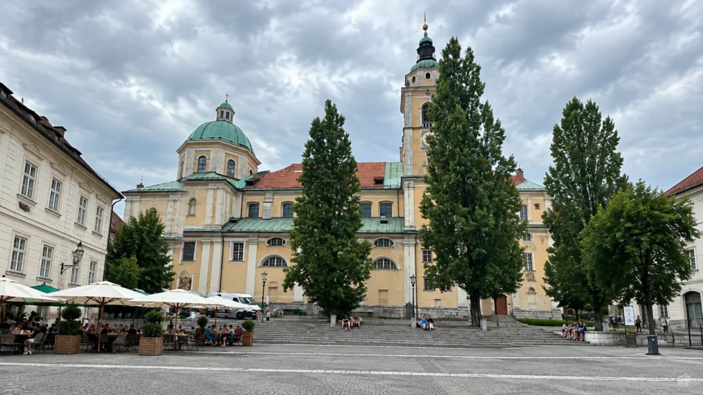St. Nicholas Cathedral in Ljubljana with its green dome and a café terrace on the square