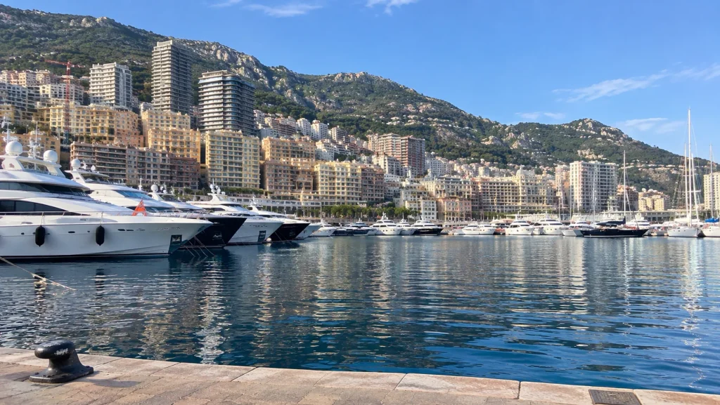 Monaco travel guide view of Port Hercule marina lined with superyachts below the hillside apartments of Monte-Carlo