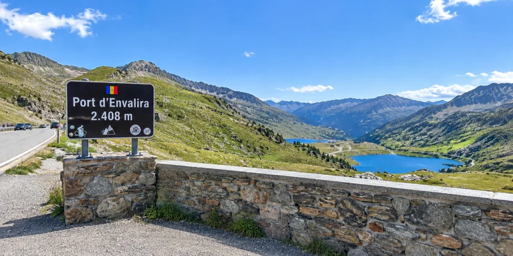 Andorra travel guide: Port d'Envalira mountain pass sign at 2,408 meters with alpine lakes below.