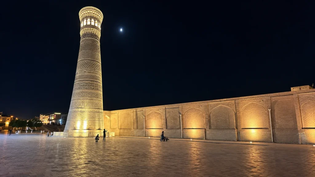 Kalon Minaret lit up at night under the moon in Bukhara’s old city
