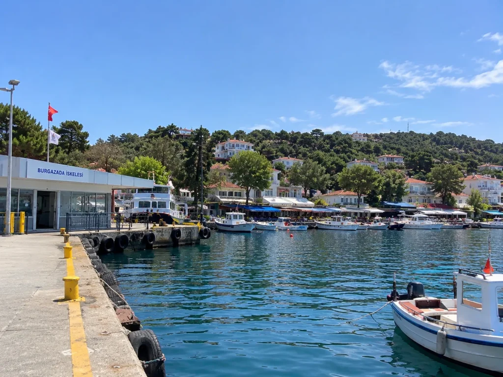 Burgazada travel guide: ferry pier with the Burgazada İskelesi sign and fishing boats along the waterfront village