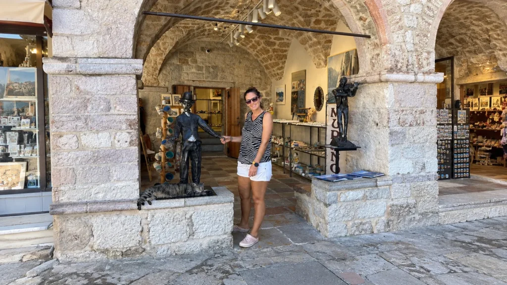 Bronze statues and a sleeping cat at a souvenir shop entrance in Kotor Old Town